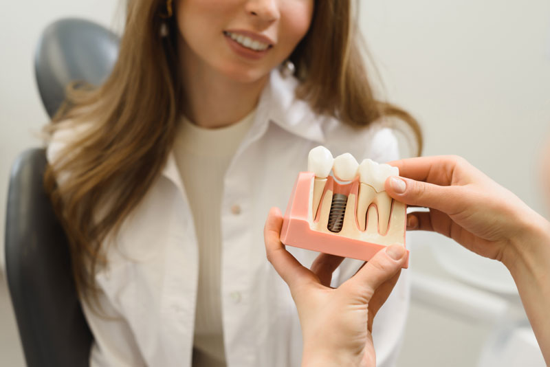 Dental Patient Getting Shown A Dental Implant Model During Her Consultation in Danbury, CT
